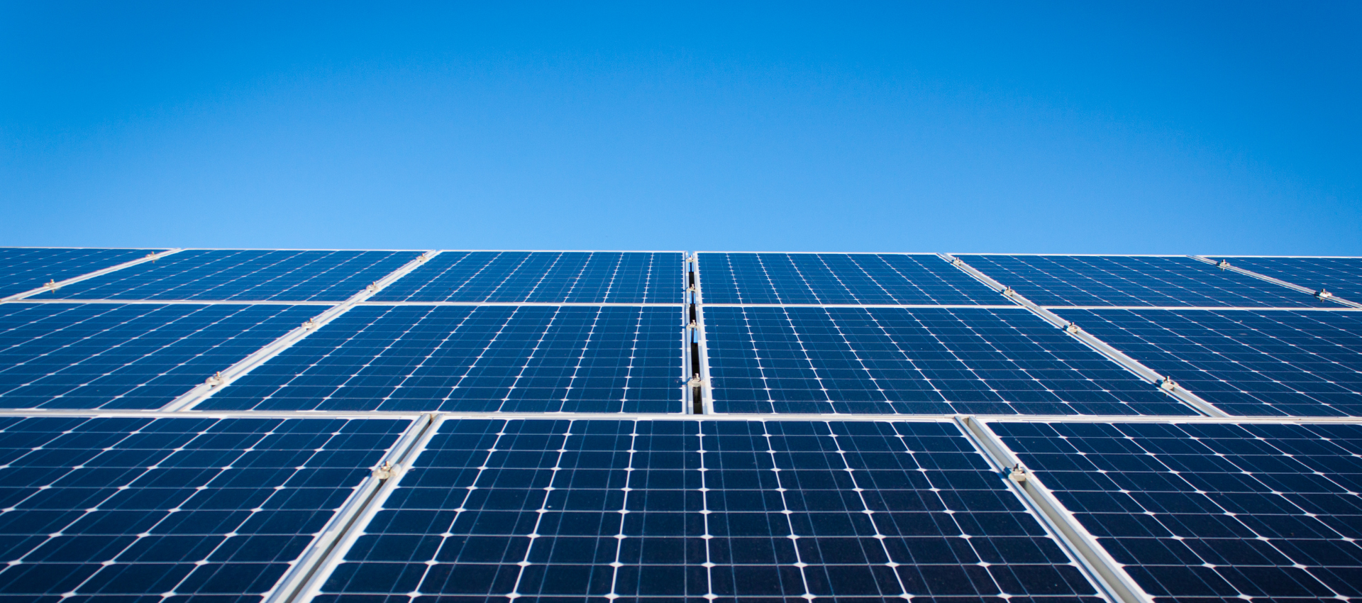 Reihen von blauen Solarpanels unter einem klaren blauen Himmel.