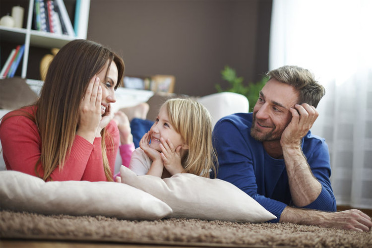 Eine Familie sitzt auf dem Boden und lacht gemeinsam.